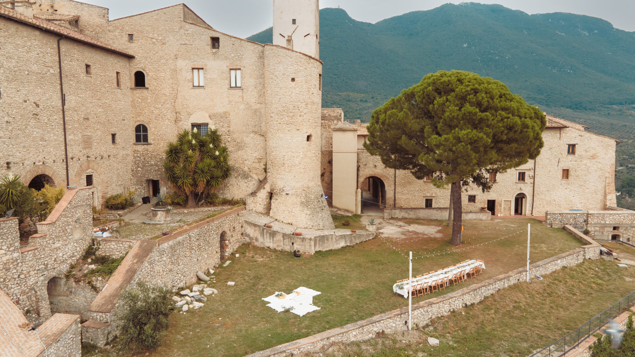 Veduta aerea della corte del castello con la torre e il pino secolare, sullo sfondo i Monti Lucretili